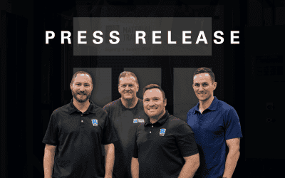 Four smiling men wearing branded shirts representing Material Transfer and Protech Equipment stand together in front of a dark background with the text "PRESS RELEASE" above them. The image relates to a press release announcing Material Transfer's expansion of their Premier Partner Network with the addition of Protech Equipment.